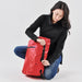 Cirrus Backpack 35 - A red backpack with a sleek design, featuring a zippered pocket and adjustable straps, held by a person in black attire.